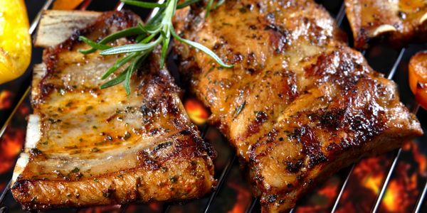 •Juicy barbecued ribs cooking over intense flames on a grill.
