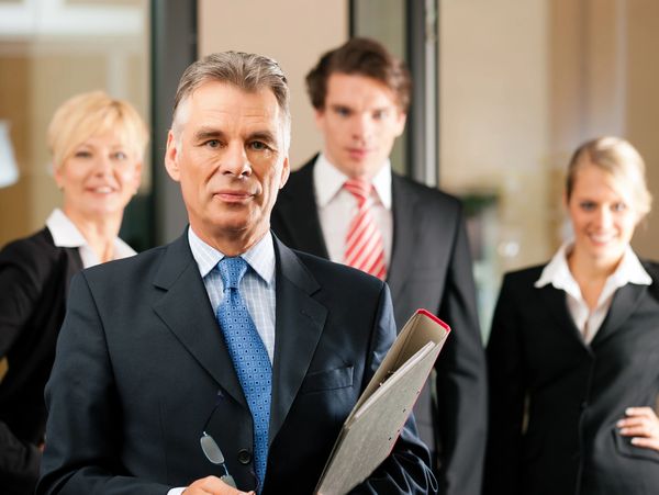 Professional businessmen and businesswomen in formal attire standing together.