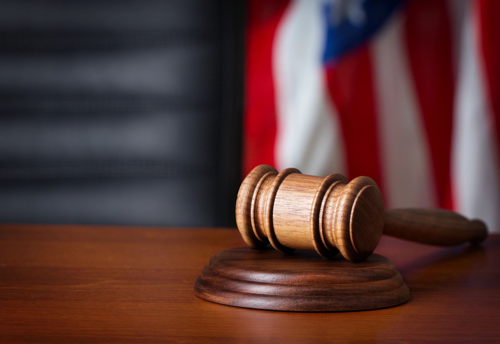 Gavel on desk with image of American flag in the background.