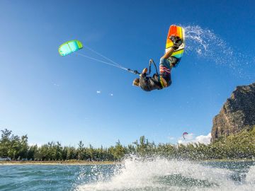 Kiteboarder performing an aerial trick over water.