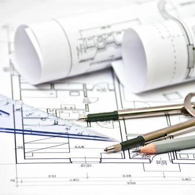 Architectural blueprints with drafting tools and pencils on a white surface.