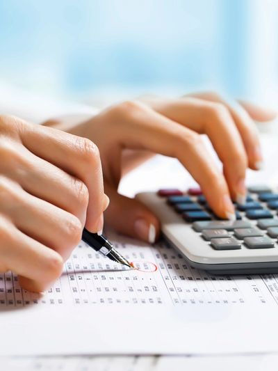 Person using a calculator and pen to review financial documents.