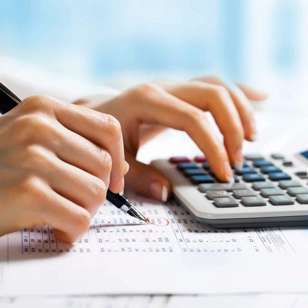 Person using a calculator and pen to check financial data on paper.