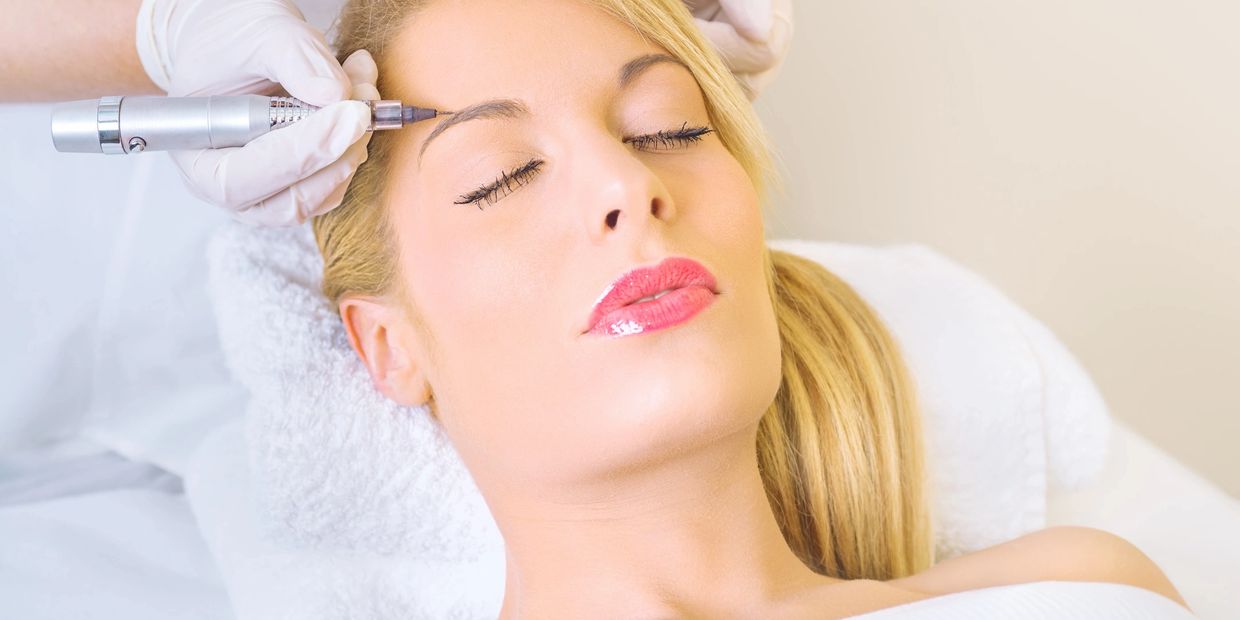 Woman receiving eyebrow tattooing with a microblading pen.