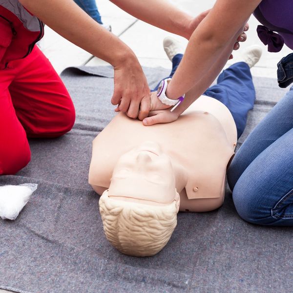 Two people practising CPR on a training manikin.