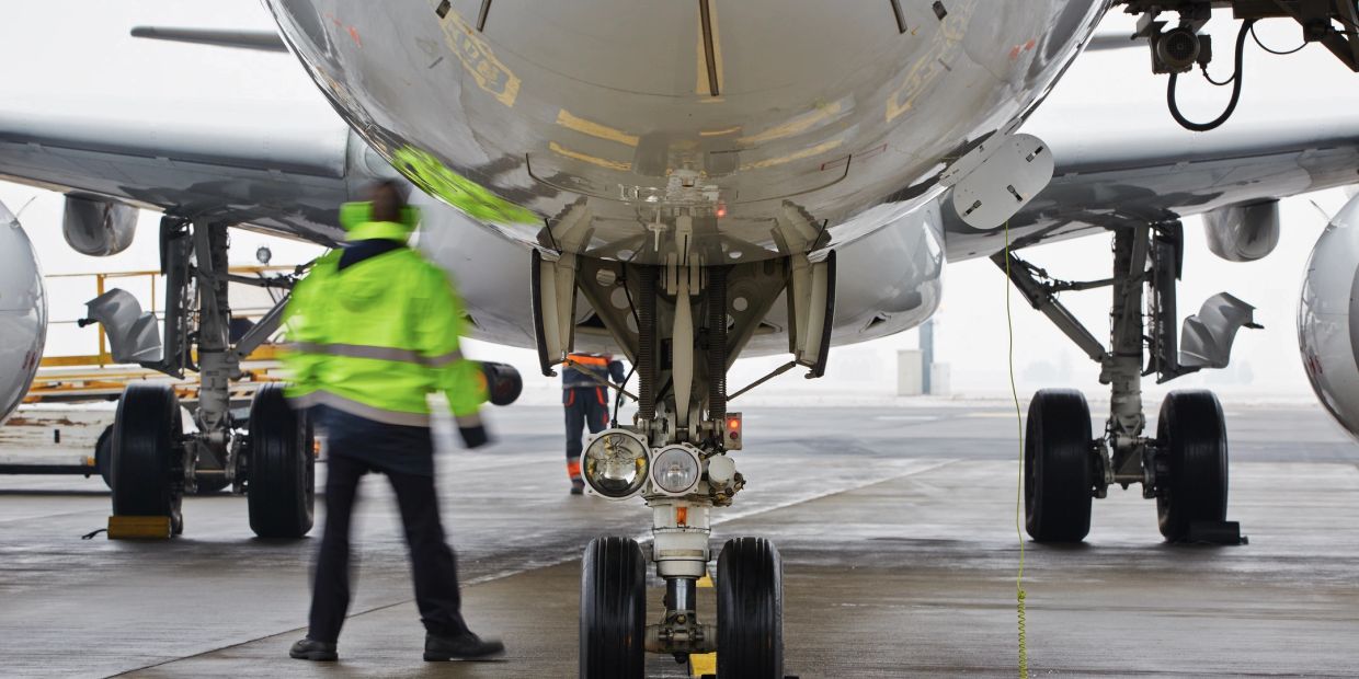 Ground crew members inspect airplane landing gear at the airport.