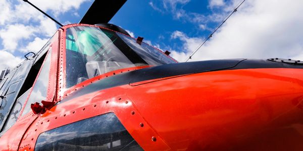 Close-up of a red and black helicopter against a blue sky.