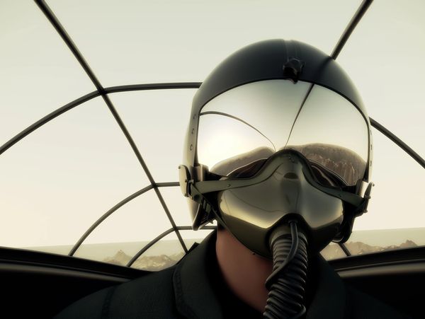 A pilot wearing a reflective helmet inside an aircraft cockpit.