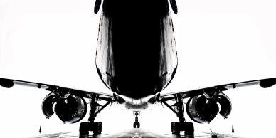 Low-angle view of an airplane on a runway with high contrast lighting.