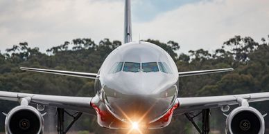 A commercial airplane taxiing on a runway with headlights on.