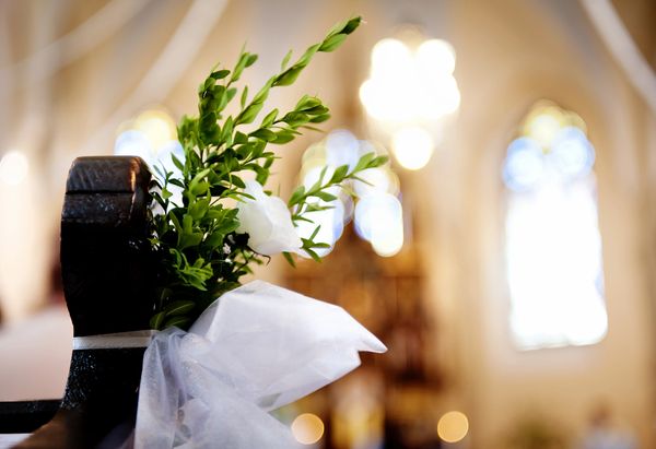Decorated church pew with white flowers and tulle for a wedding.