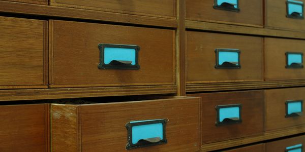 Wooden drawers with turquoise label holders, one slightly open.