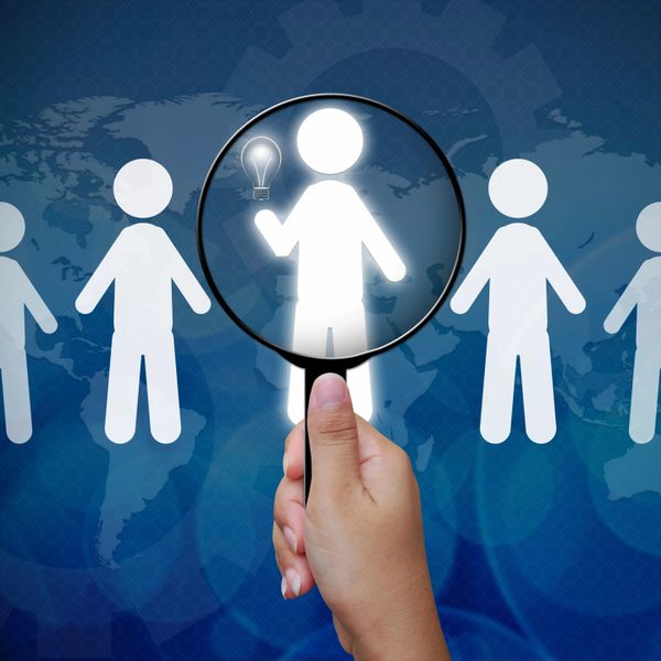 Magnifying a figure with a light bulb symbolizing a bright idea among others.