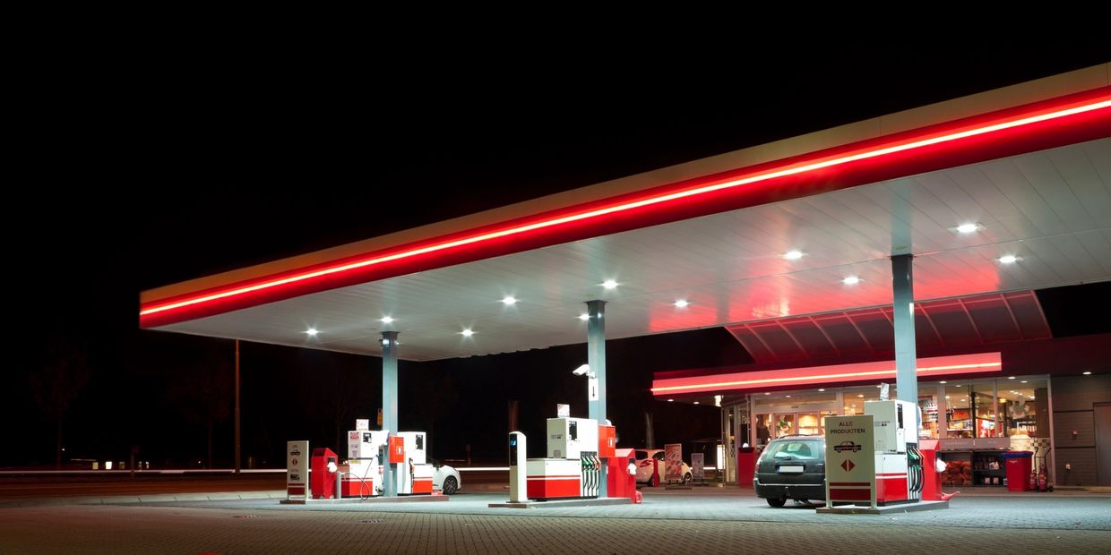 A well-lit gas station at night with a car refueling.