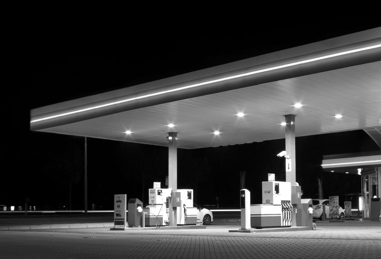 Empty gas station illuminated at night in black and white.