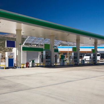Empty gas station with multiple fuel pumps under a clear blue sky.