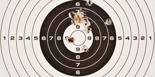 Paper bullseye with several shots near the center