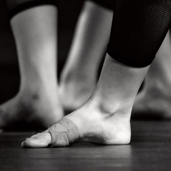 Close-up of a dancer's foot with taped toes on stage floor.