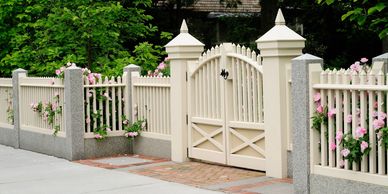 Elegant white picket fence with blooming pink flowers and a double gate.
