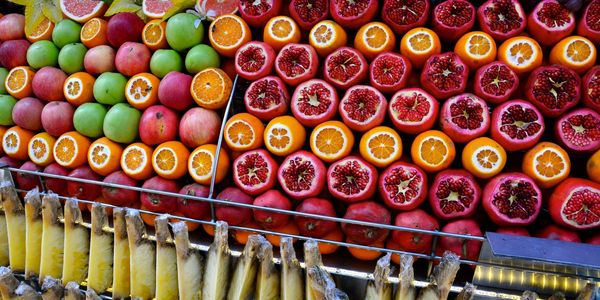 Colorful display of fresh fruits including apples, pomegranates, oranges, and bananas.