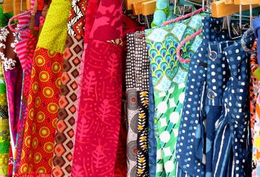 Colorful patterned fabrics hanging on display with clips.