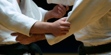 Two martial artists gripping each other's uniforms during practice.