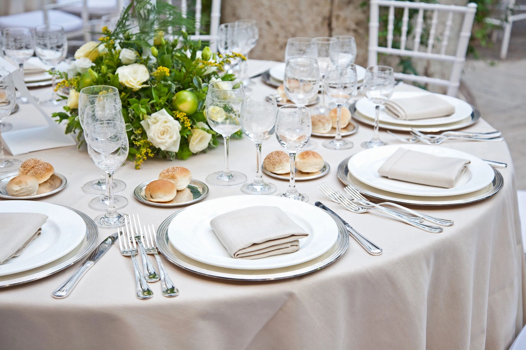 Elegant wedding table setting with white roses and glassware.