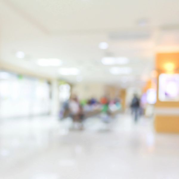 Blurred hospital waiting area with people and bright lighting.