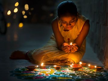 A girl lighting a diya for celebration.