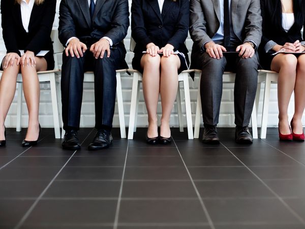 Five business professionals sitting in a row, waiting.