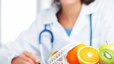 Doctor holding a measuring tape around oranges, symbolizing health and nutrition.