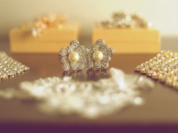 Pearl and diamond flower earrings with jewelry in the background.