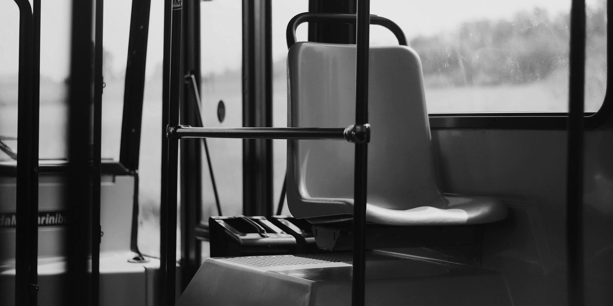 Empty plastic bus seat in black and white.