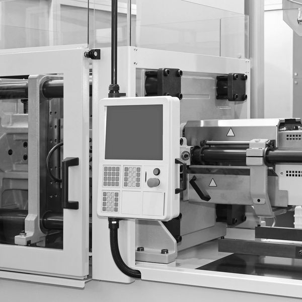 Modern injection molding machine with control panel and safety enclosure.