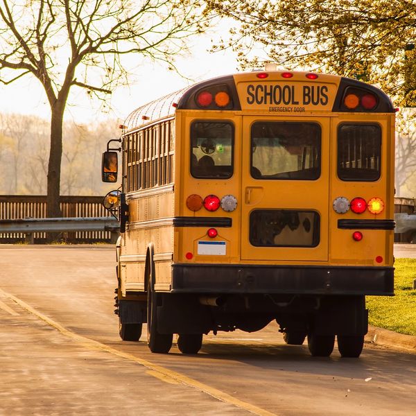 Yellow school bus on a quiet road during golden hour.