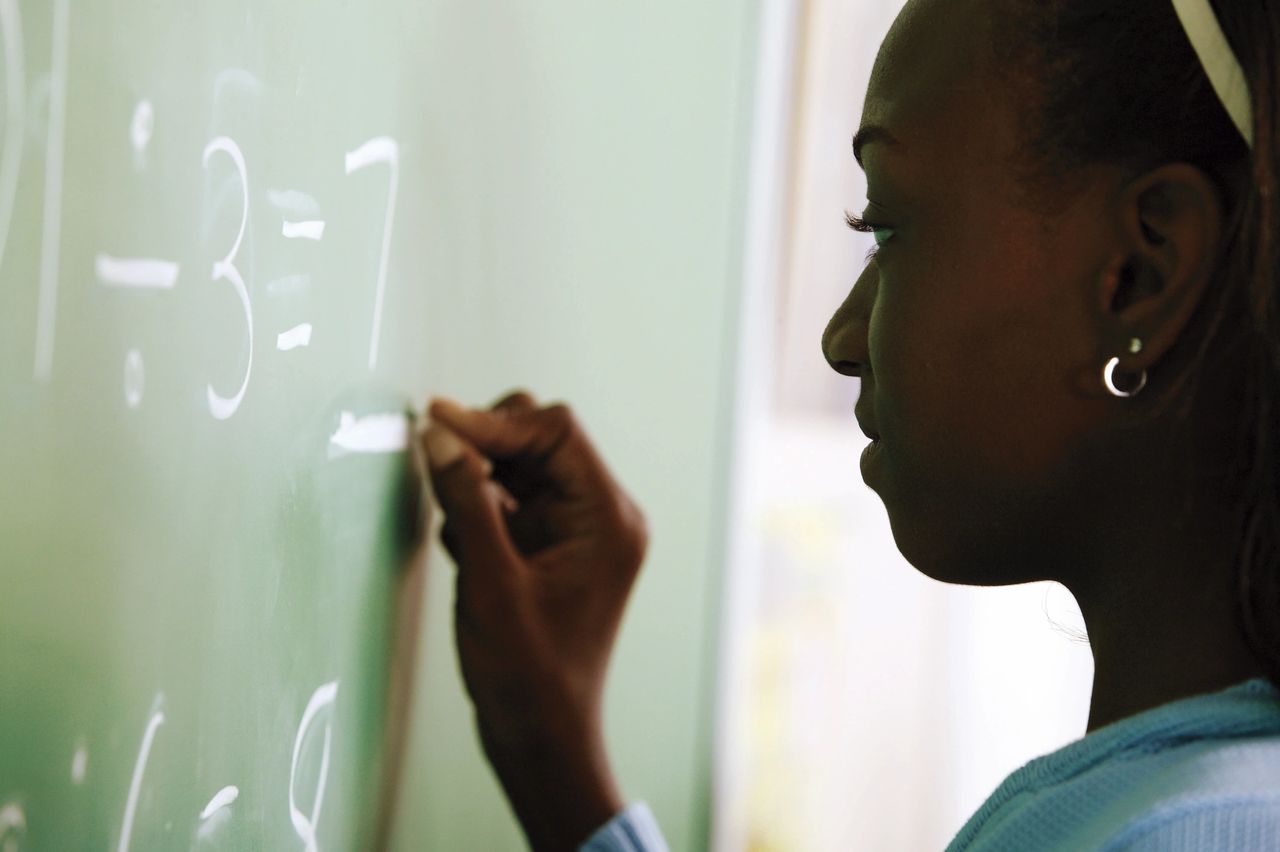 Mathematical equations being completed at the chalkboard by a student.