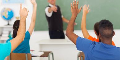 students raising hands in classroom