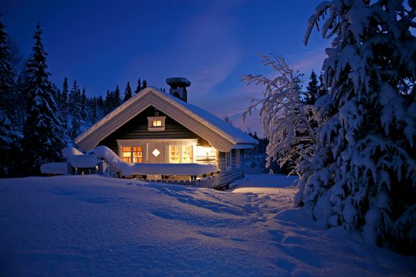 A snow-covered home set in the snowy woods.
