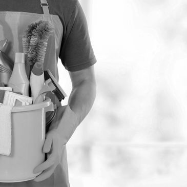 Person holding a bucket full of cleaning supplies and wearing gloves.