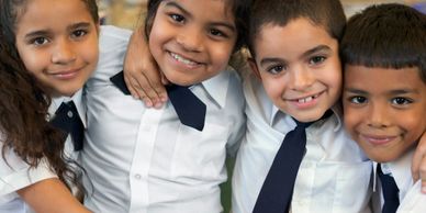 4 children at school, in white shirts and wearing blue ties (two boys and two girls)