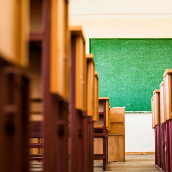 Empty classroom with desks and a green chalkboard.