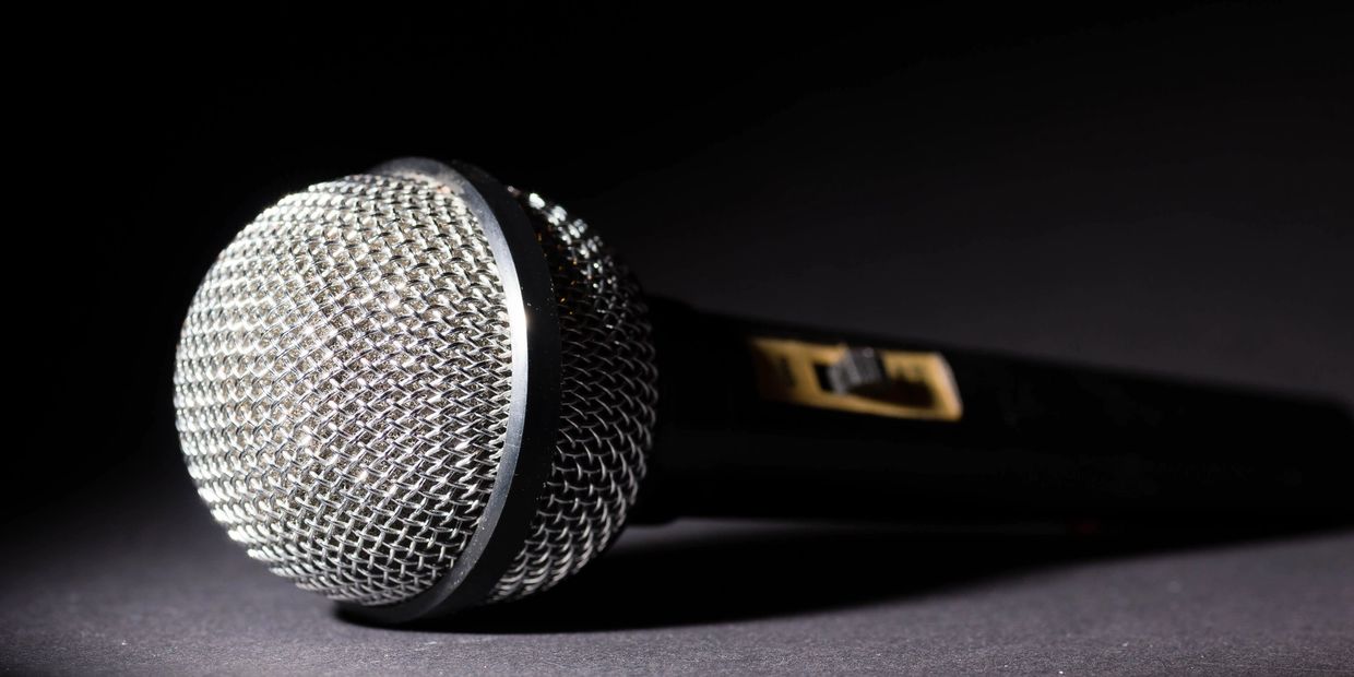 Close-up of a microphone with a metal mesh head on a dark surface.