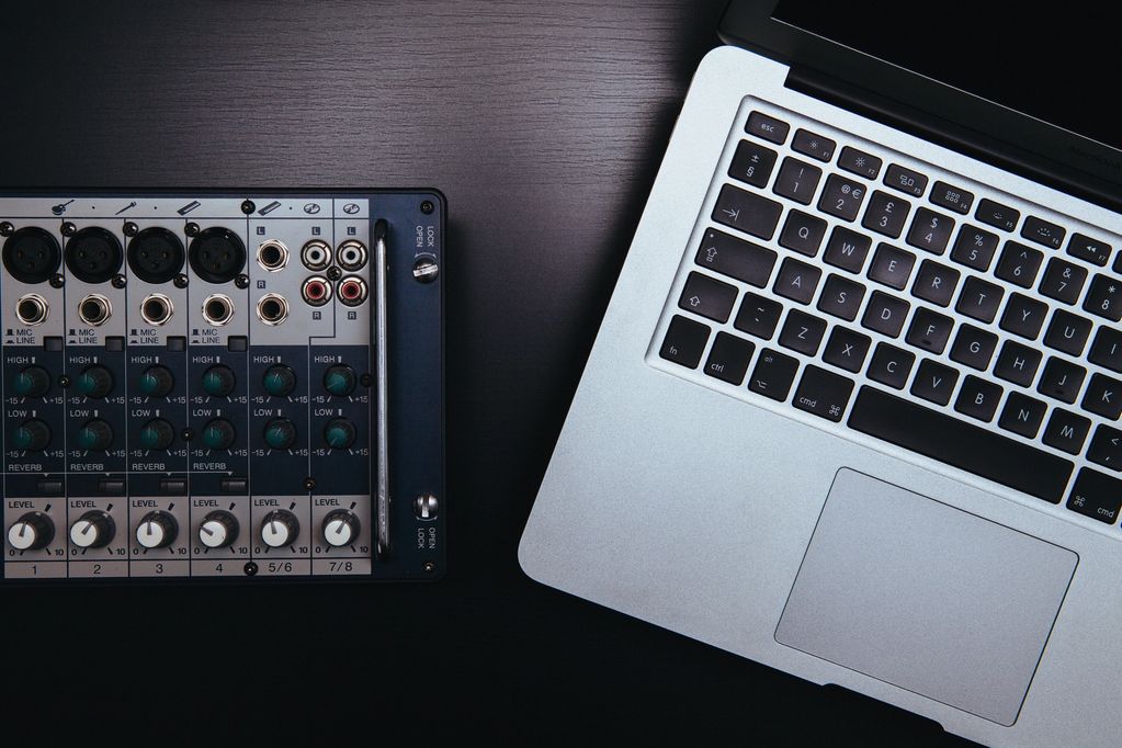 Audio mixer and laptop on a dark surface.