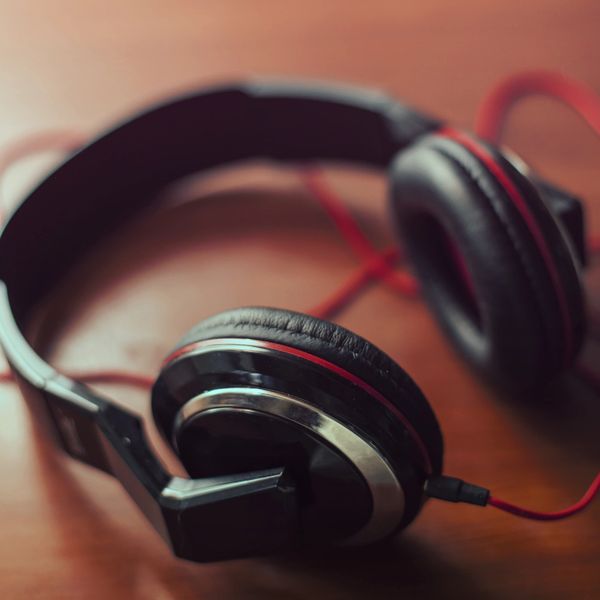 Close-up of black over-ear headphones with red accents on a wooden surface.