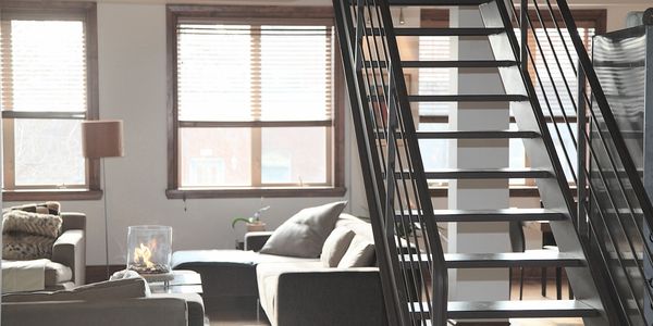 Home with stairs up to next level. Couch and love seat.