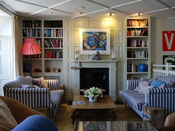 Cozy living room with striped sofas and built-in bookshelves around a fireplace.