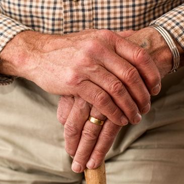 A male resident resting with his hands on his cane.