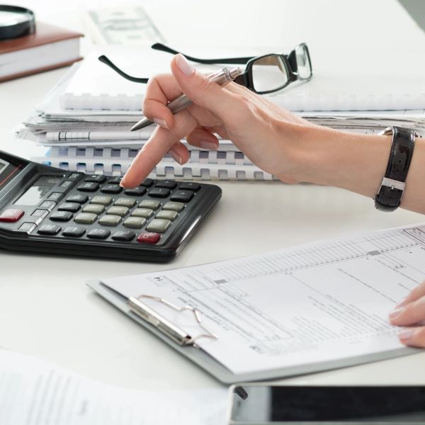 Person using calculator with paperwork on desk.