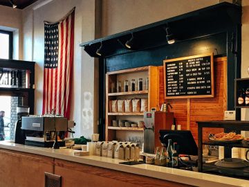 Cozy coffee shop interior with American flag and menu board.