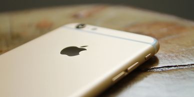 Close-up of a gold iPhone lying on a wooden surface.